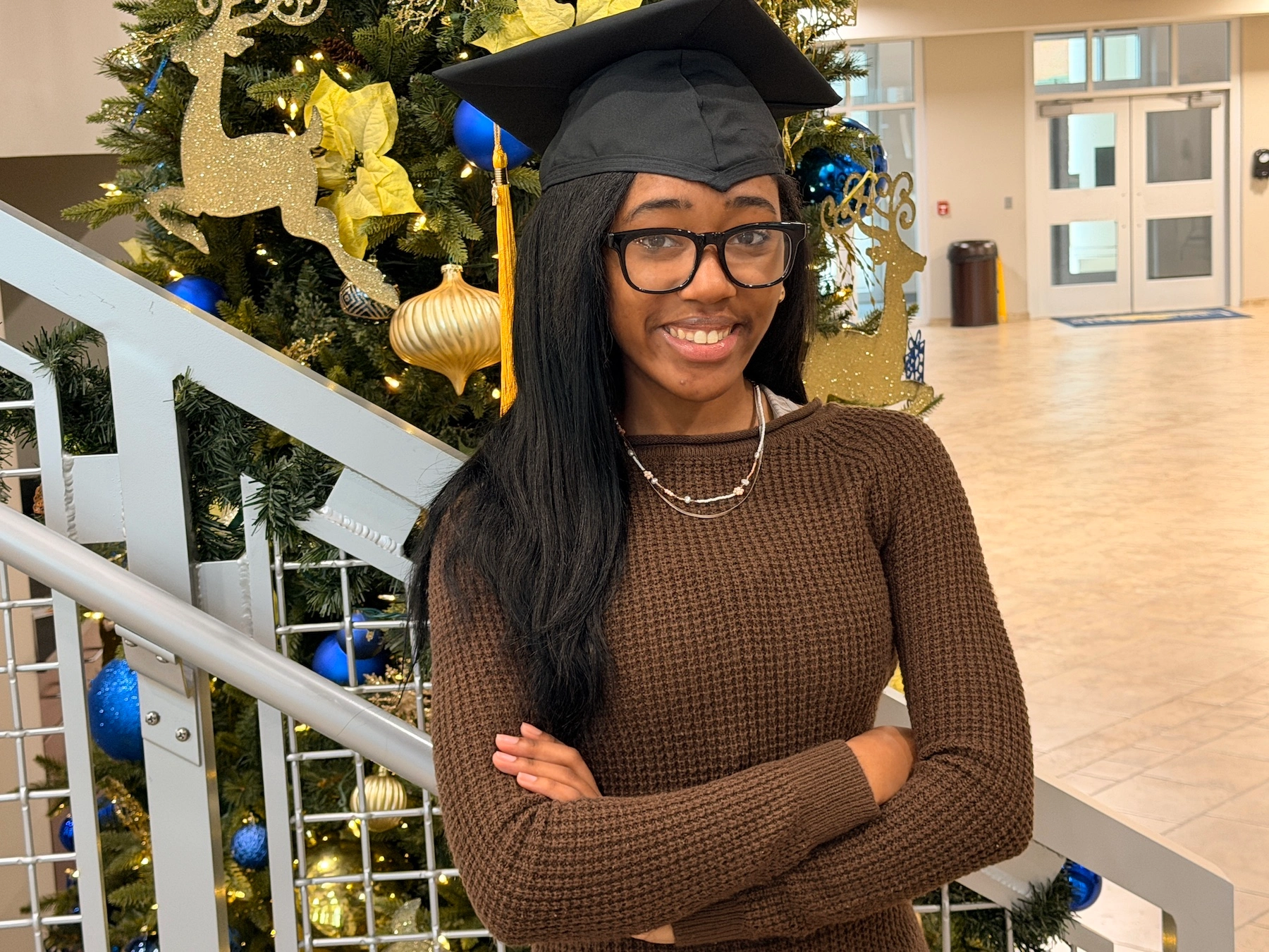 A girl wearing christmas hat and standing near christmas tree