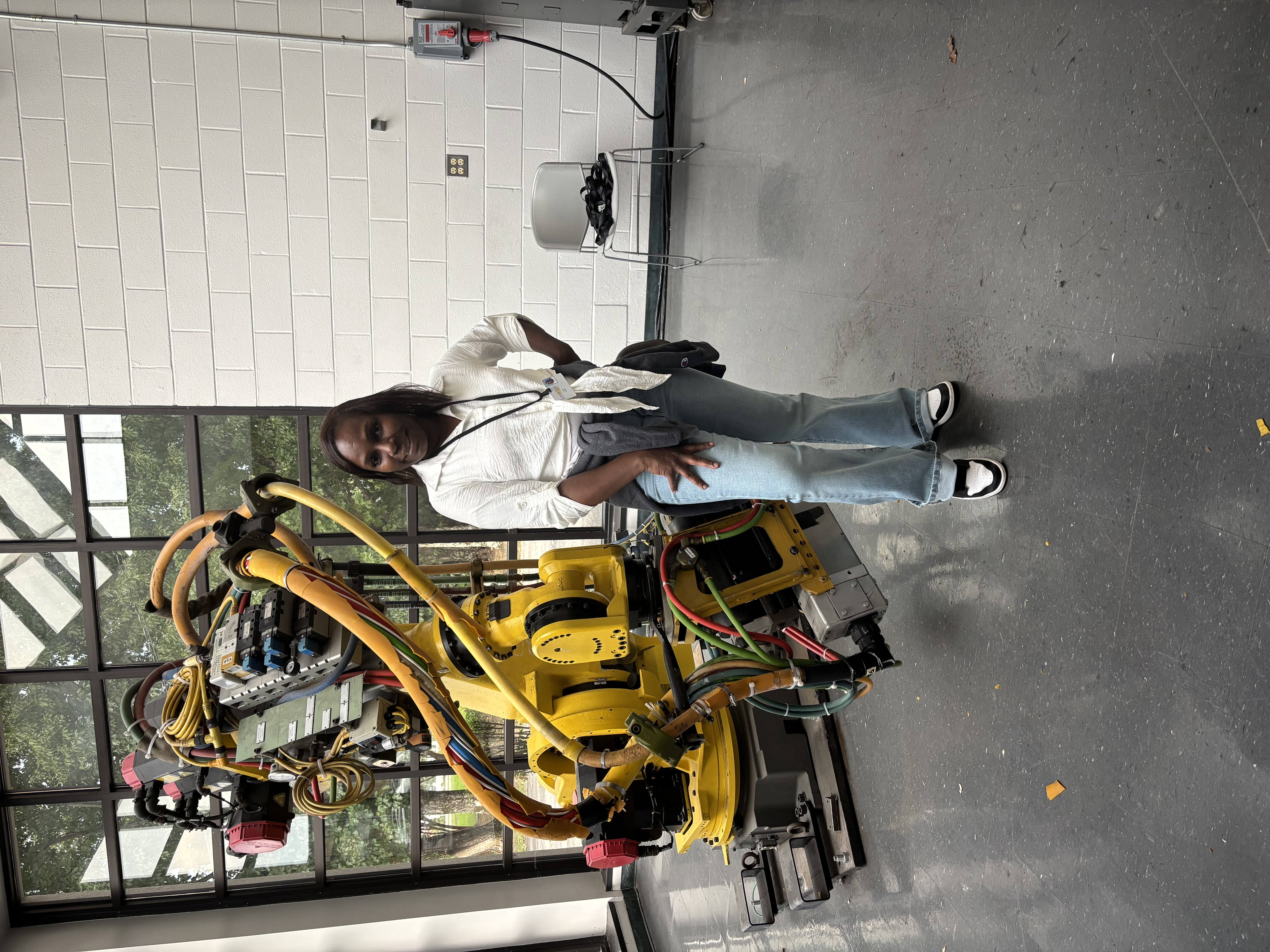Lawson State student Latoya Gaines stands beside an industrial robotic arm in a campus lab